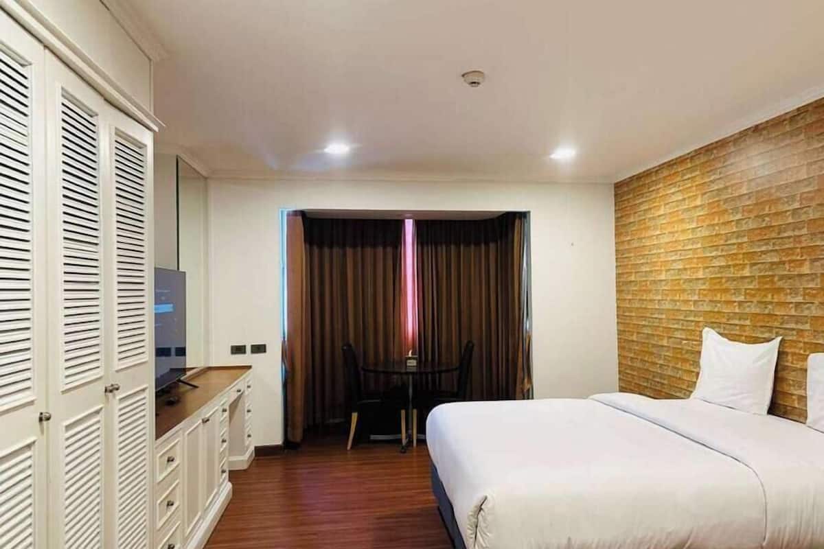 A hotel room with a bed, a desk, and a wardrobe.