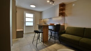 A compact living space with a kitchenette, a green sofa, and a small dining area. - Villa Betina - Apartman Ambienta by Villas Guide (Lovran)