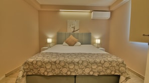 A hotel room with a bed, two bedside lamps, an air conditioner, and a wall-mounted artwork. - Villa Betina - Apartman Ambienta by Villas Guide (Lovran)