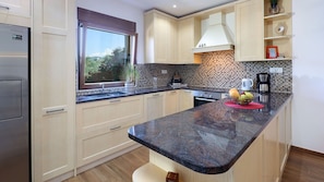 A modern kitchen with a large island, stainless steel appliances, and a view of greenery outside. - Villa Kostrena in a green oasis by Villas Guide (Kostrena)