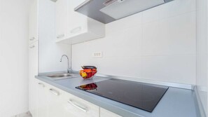 Eine moderne Küche mit eingebautem Herd, Spüle und einer Obstschale auf der Arbeitsfläche.