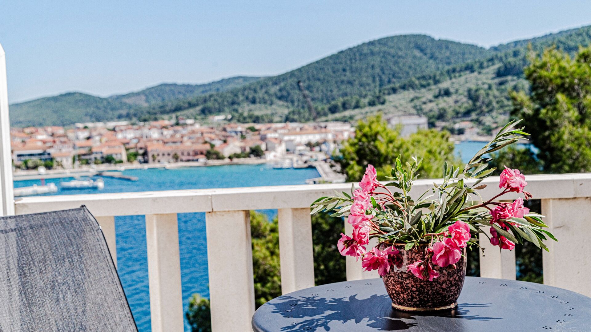 A balcony with a potted plant and a view of a coastal town.