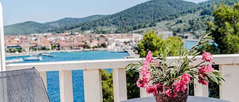 A balcony with a potted plant and a view of a coastal town.