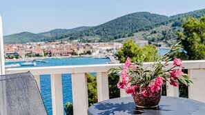 Ein Balkon mit einem Blumentopf und Blick auf eine Küstenstadt.