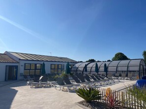 Een hotel met een overdekt terras, lounge stoelen en een serre.