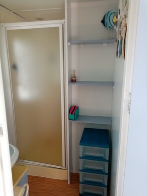 Een kast met schuifdeur, planken en opbergmanden.