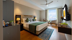 A hotel room with a large bed, a desk, a chair, a TV, and a view of the sky. - The Lohias Premium - Delhi IGI Airport (New Delhi)
