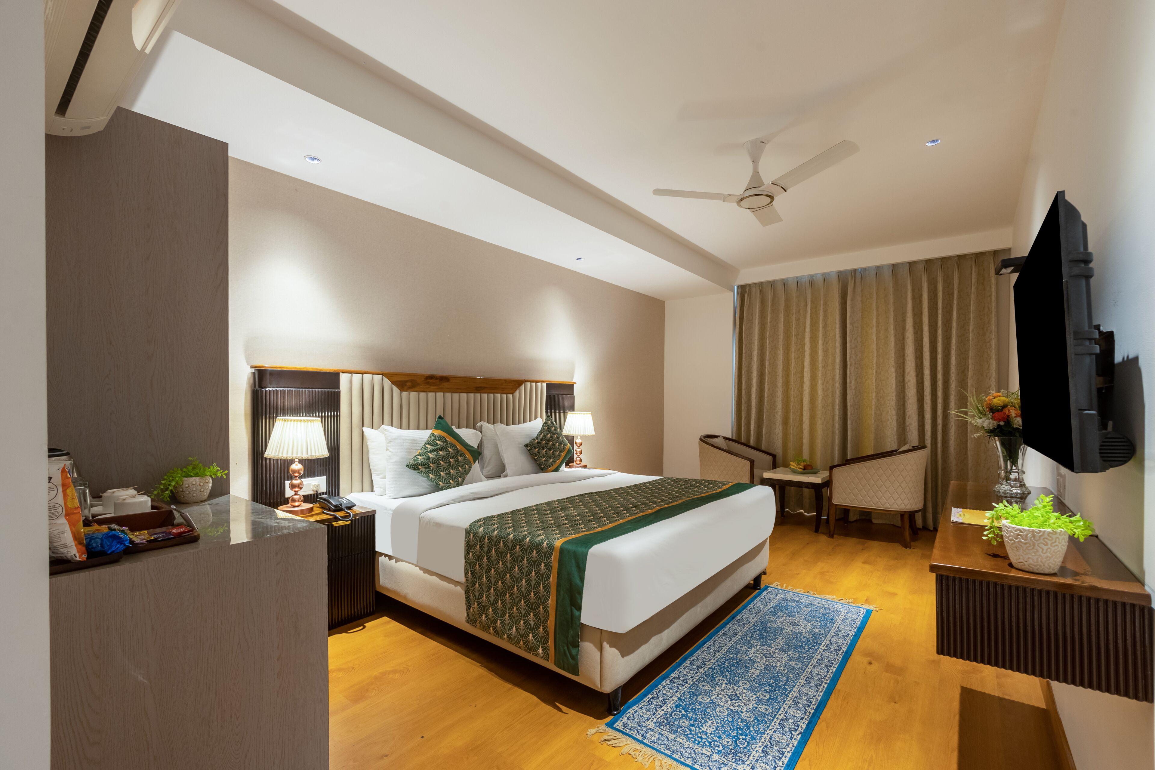 A hotel room with a bed, a desk, a chair, a TV, and a ceiling fan.