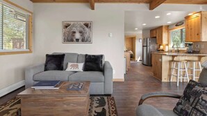 En stue med sofa, sofabord og bjørne-inspireret vægkunst.