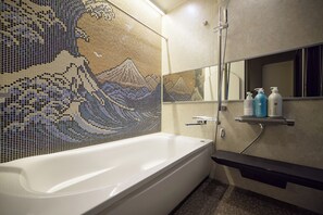 A modern bathroom with a large bathtub, a mosaic wall, and a shelf with toiletries. - Blossom House Shibuya (Shibuyakumaruyamacho)