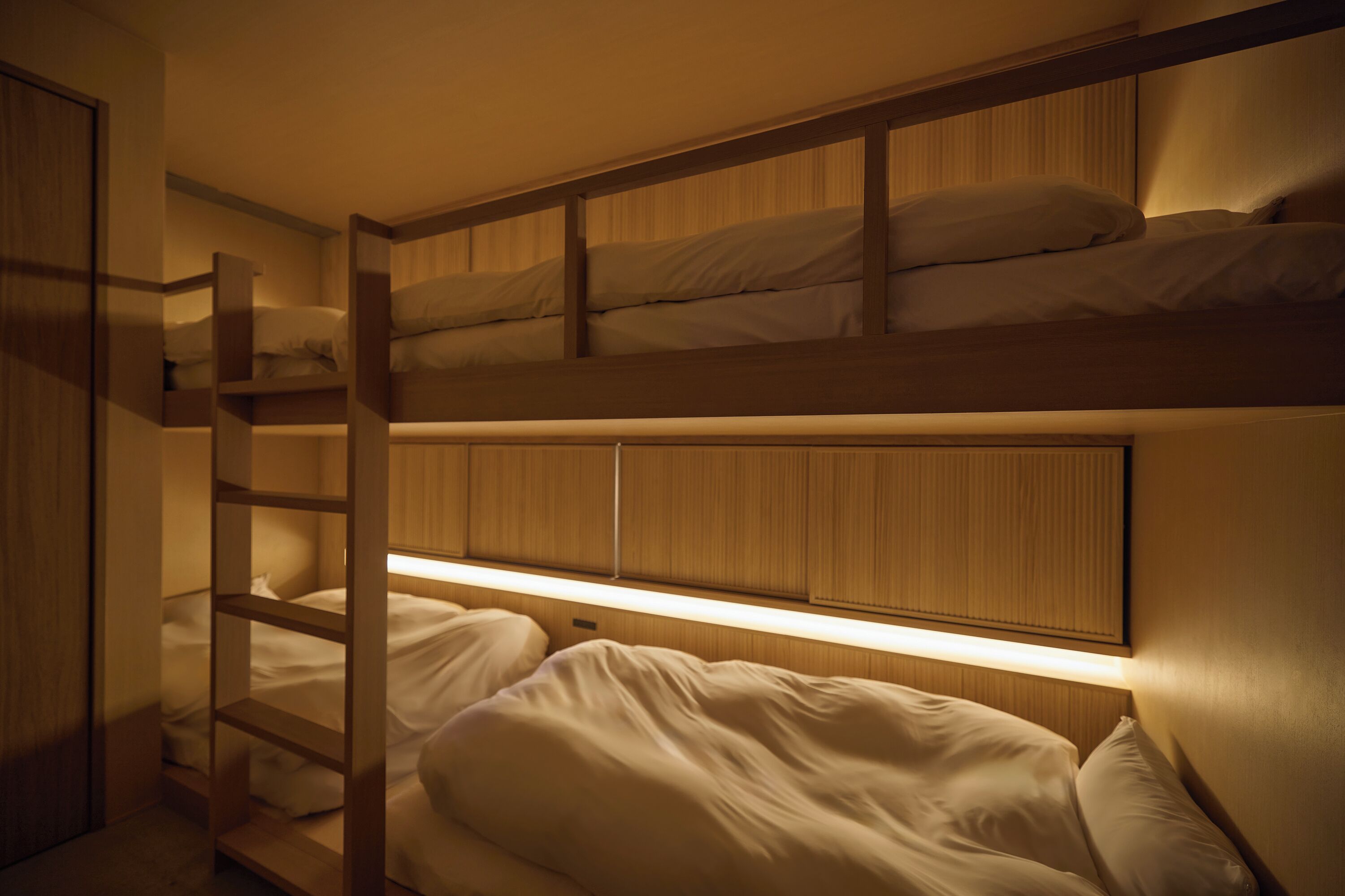 A bunk bed room with a wooden headboard and a ladder.
