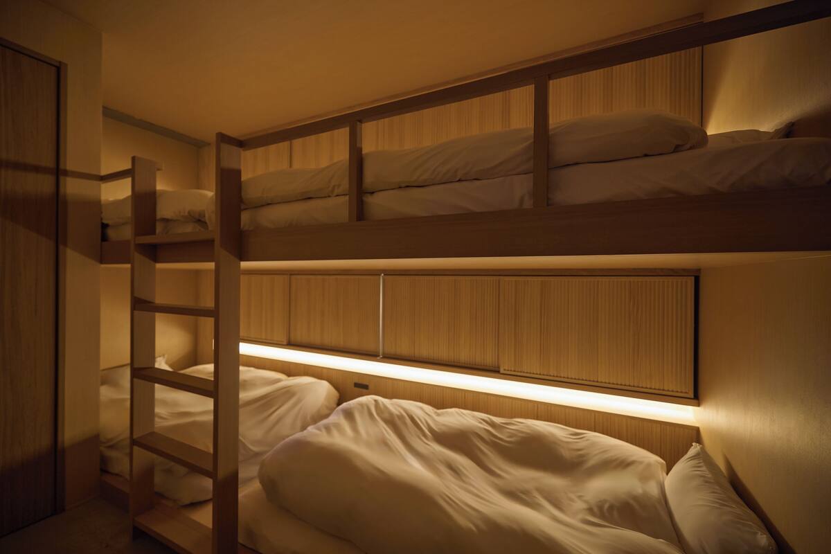 A bunk bed room with a wooden headboard and a ladder.