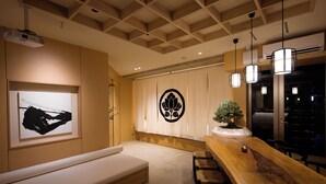A modern interior with a wooden dining table, a bench, a projector, and a decorative wall piece.