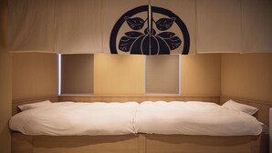 A double bed with a wooden headboard, two bedside tables, and a large window with blinds.
