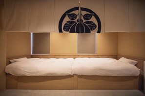 A double bed with a wooden headboard, two bedside tables, and a large window with blinds. - Blossom House Shibuya (Shibuyakumaruyamacho)