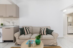 A modern living room with a beige sofa, a coffee table, and a kitchen area in the background.