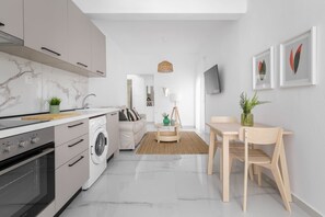 Una cocina moderna con horno empotrado, lavadora y zona de comedor con mesa y sillas.