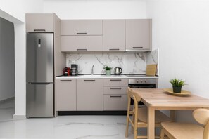 A modern kitchen with a built-in refrigerator, a stove, and a dining area with a wooden table and chairs.
