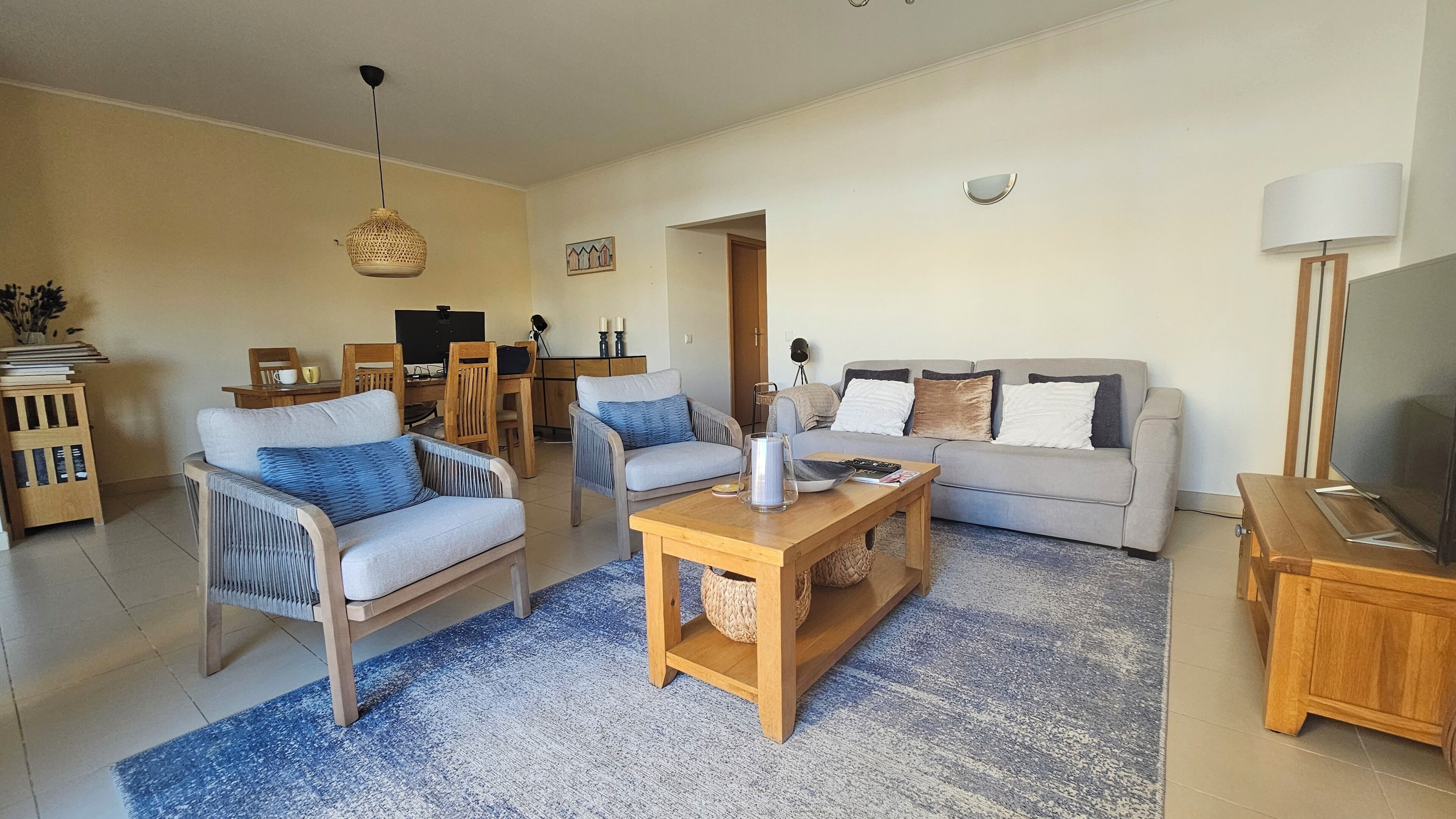 Ein Wohnzimmer mit einer Couch, zwei Sesseln, einem Couchtisch und einem Fernseher.