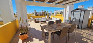 A patio with outdoor furniture, a table, and a small shed. - Palmview Penthouse Algarve - sea view, pool, golf & fantastic roof terrace (Conceicao de Tavira)
