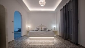 A bedroom with a bed, bedside lamps, a ceiling light, and a view into another room. - THE F SUITES (KARTERADOS)