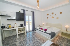 A hotel room with a bed, a desk, a sink, and a view of the outside. - THE F SUITES (KARTERADOS)