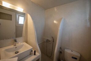 A bathroom with a sink, mirror, shower, and toilet. - THE F SUITES (KARTERADOS)