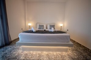 Une chambre d’hôtel moderne avec un lit, des lampes de chevet et un sol en marbre.