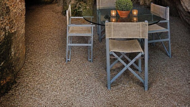 An outdoor dining area with a table and chairs, a hanging lantern, and a rocky cave background. - Cottage with garden cave in the hills of Pietrasanta (Monteggiori)