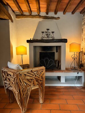 Un intérieur rustique avec une cheminée, des meubles en bois et un sol carrelé.