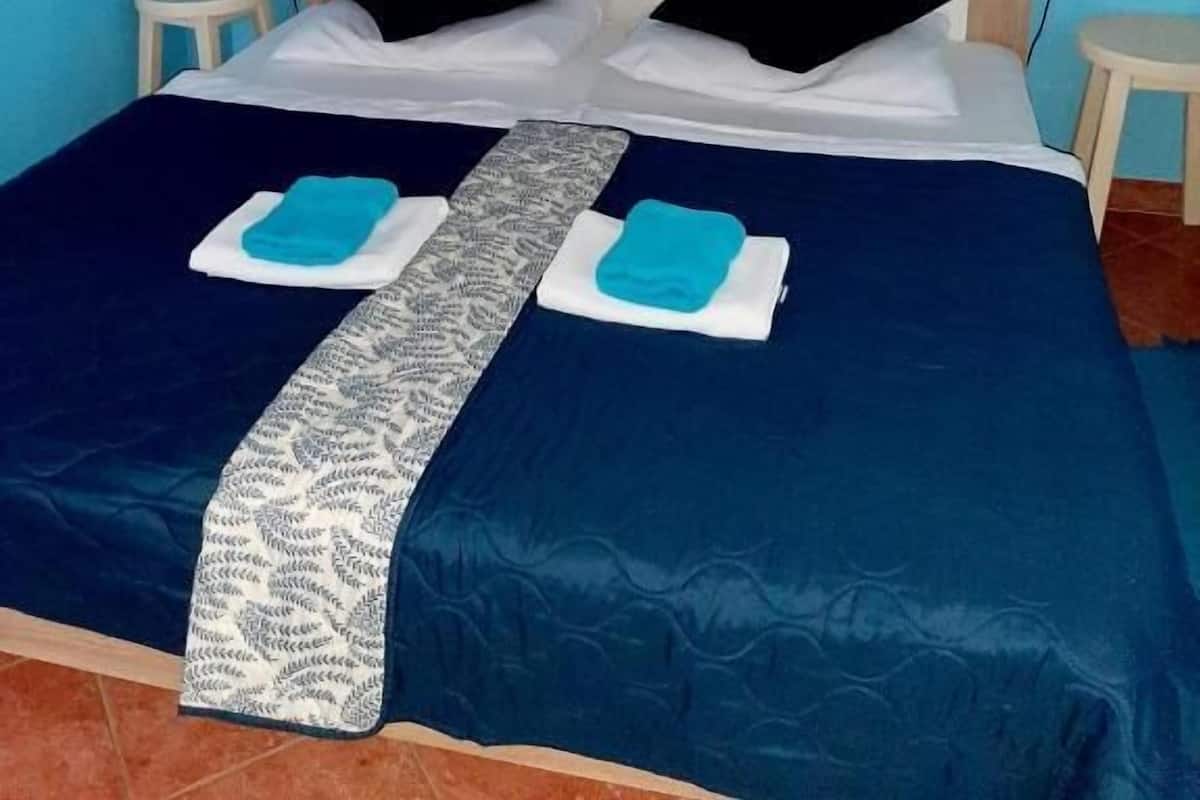 A bed with a patterned bedspread, two pillows, and two towels.