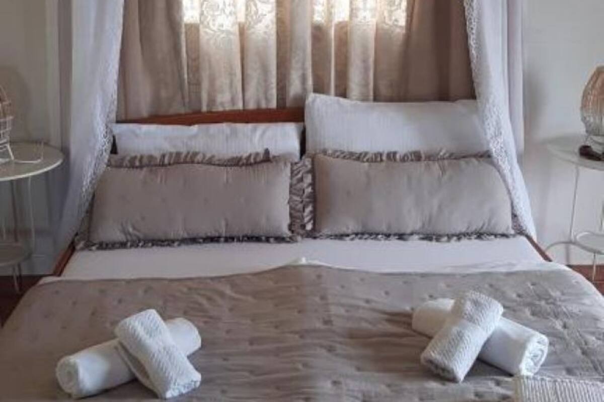 A bed with a canopy, pillows, and rolled towels.