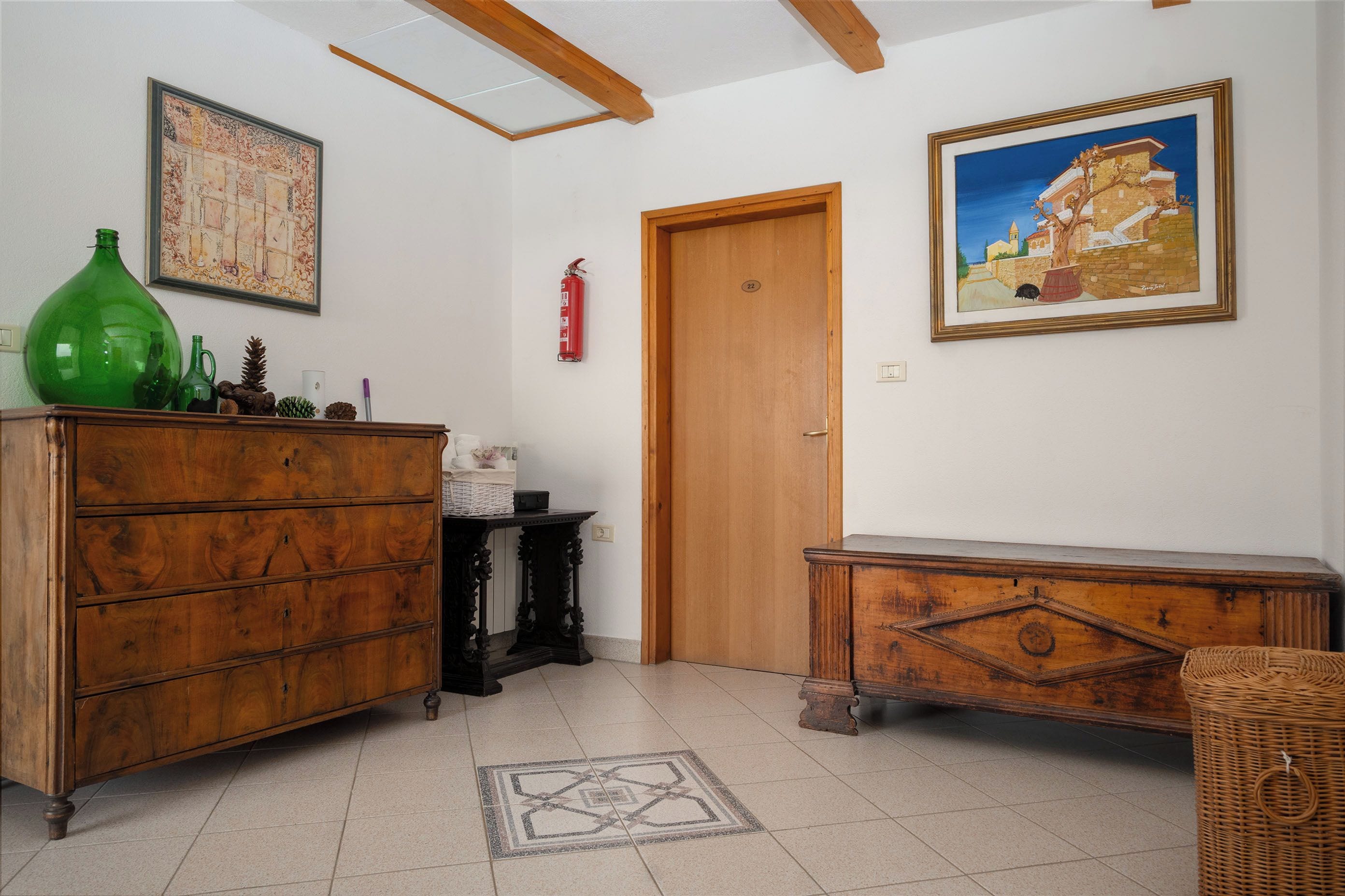 Quarto com mobiliário de madeira, extintor de incêndio e duas obras de arte emolduradas nas paredes.