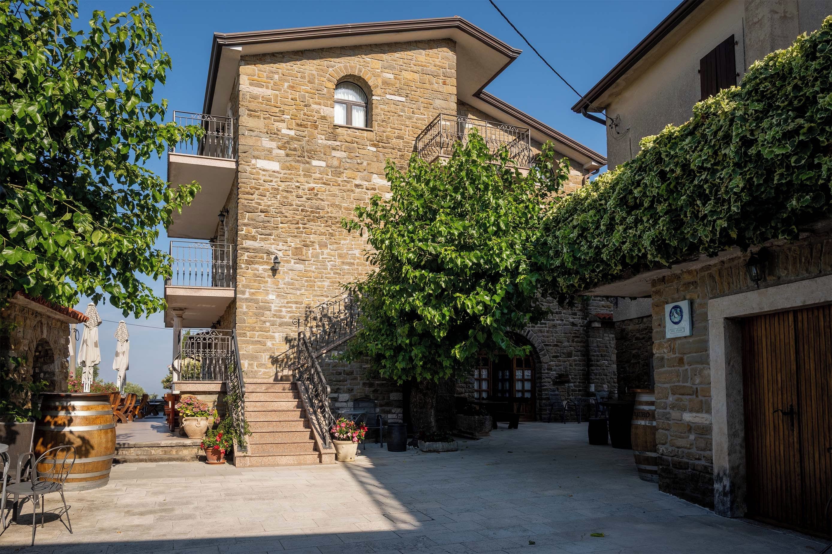 Un edificio de piedra con un balcón, un patio empedrado y una puerta de madera.