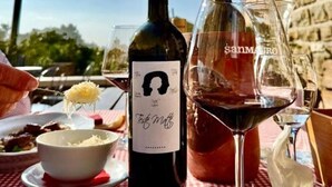 Una mesa con una botella de vino, copas y un plato de comida.