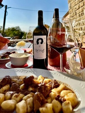 A table with a bottle of wine, glasses, and a plate of food.