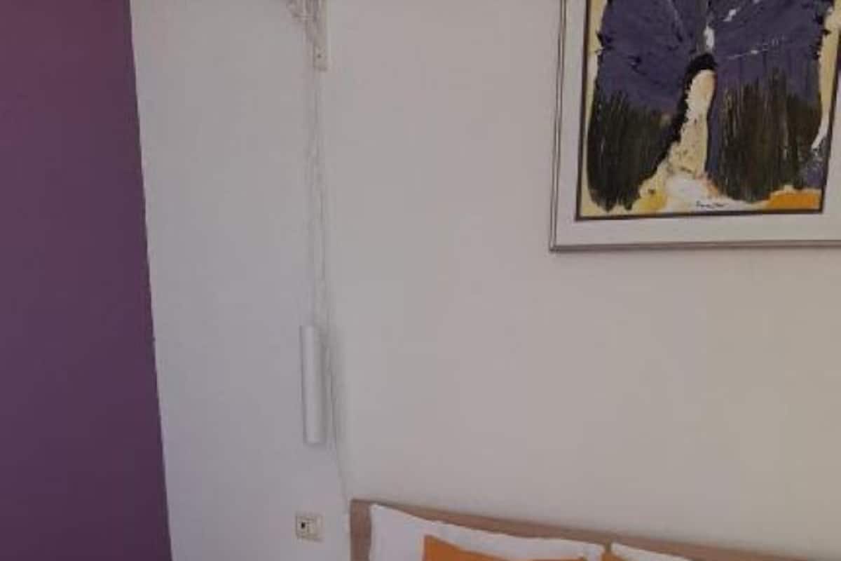 A neatly made bed with white linens, two pillows, and two folded towels.