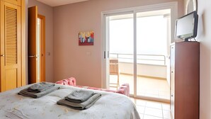 A bedroom with a bed, a TV, a painting, a balcony, and a door. - Family villa Green House - Private pool - Garden - Tenerife North Bajamar (Bajamar)