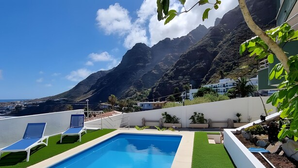 A swimming pool with lounge chairs, a view of mountains, and a building with white walls and green plants. - Family villa Green House - Private pool - Garden - Tenerife North Bajamar (Bajamar)
