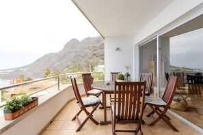 A balcony with a table and chairs, a potted plant, and a view of mountains. - Family villa Green House - Private pool - Garden - Tenerife North Bajamar (Bajamar)