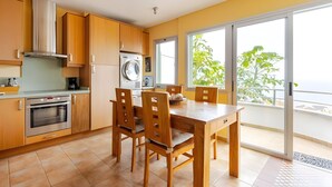 A modern kitchen with wooden cabinets, a built-in oven, and a large window overlooking a balcony. - Family villa Green House - Private pool - Garden - Tenerife North Bajamar (Bajamar)