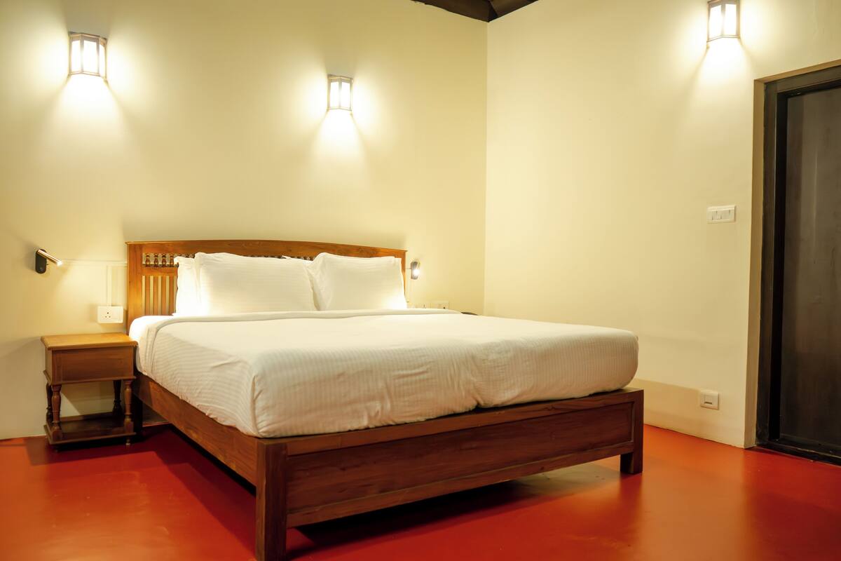 Una cama bien hecha con sábanas blancas, cabecera de madera y dos lámparas de noche.