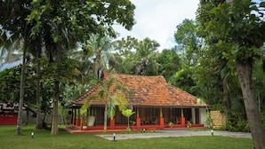 A house with a tiled roof, surrounded by lush greenery and palm trees.
