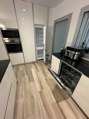 Une cuisine moderne dotée d’appareils électroménagers intégrés, d’un lave-vaisselle et d’une porte coulissante.