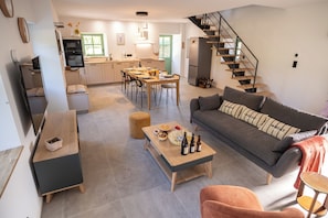 Ein moderner Wohnbereich mit Essplatz, Sofa und Treppe.
