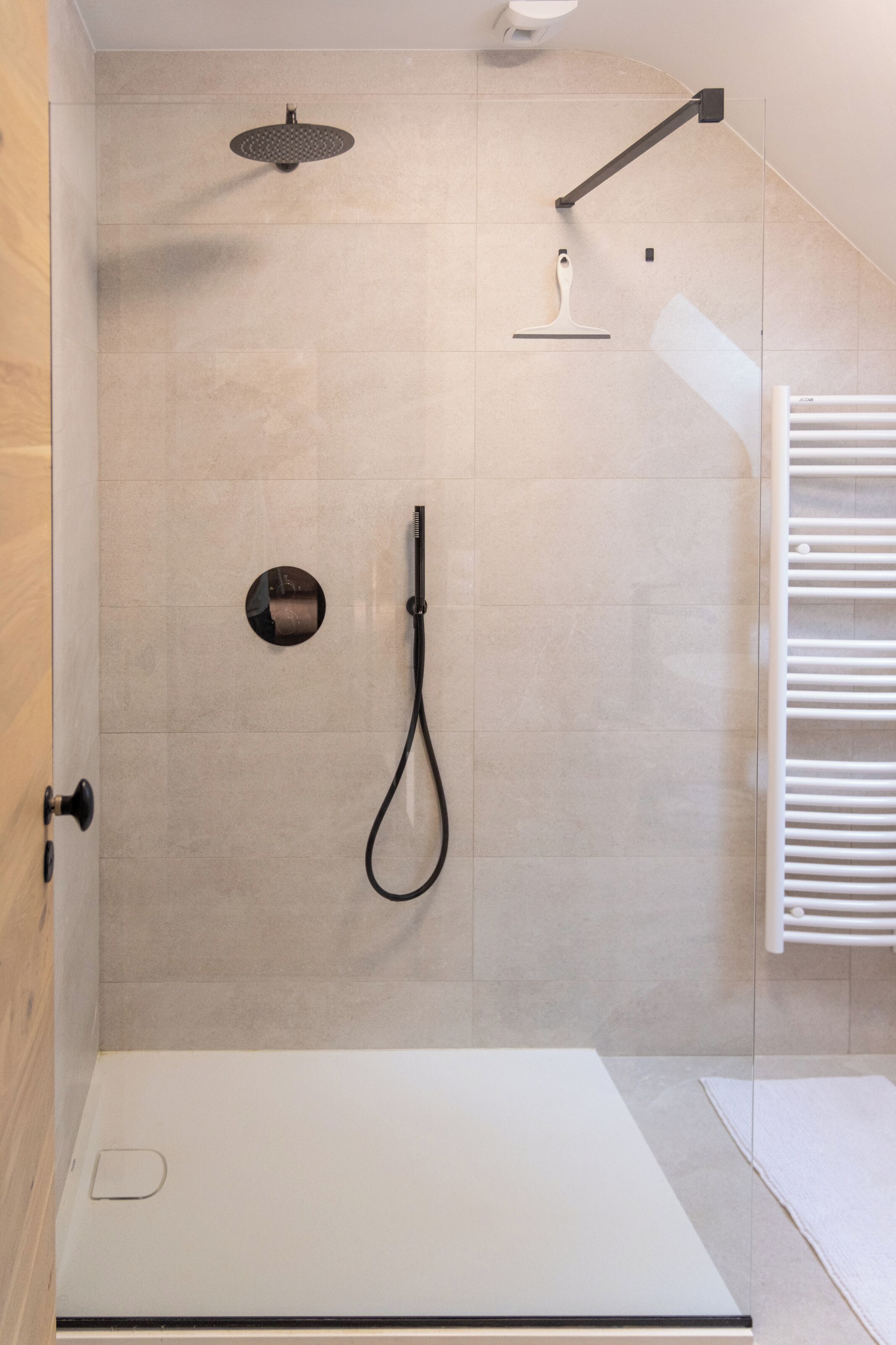 A modern shower with a handheld showerhead, a wall-mounted faucet, and a control panel.