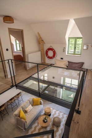 Ein geräumiger Loft mit Glasboden, Grundriss, Essbereich mit Sofa und Stühlen sowie Blick ins Freie.