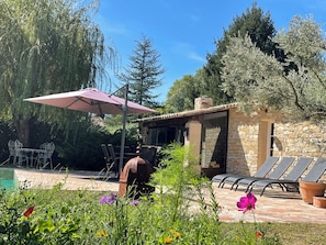 Un bĂątiment en pierre dotĂ© dâune piscine, dâun espace extĂ©rieur amĂ©nagĂ© et dâune pergola.