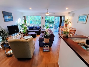 A spacious living room with a TV, sofas, a dining area, and a view of the outdoors.