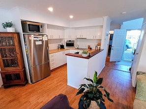 A modern kitchen with white cabinets, stainless steel appliances, and a wooden island.